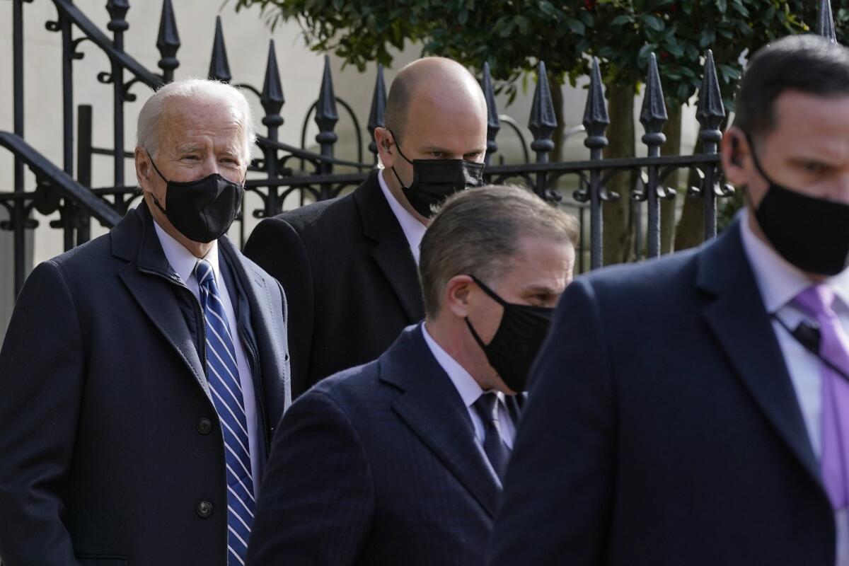 President Biden departs Holy Trinity Catholic Church with three men near him.