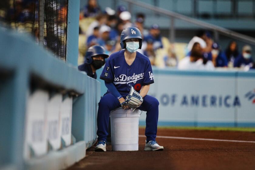 LOS ANGELES, CA - AUGUST 20, 2021: Even the Los Angeles Dodgers ball girl is required to wear a mask as tonight is the beginning of a new LA County health mandate requiring venues with more than 10,000 people to require masks at Dodger Stadium on August 20, 2021 in Los Angeles, California.(Gina Ferazzi / Los Angeles Times)