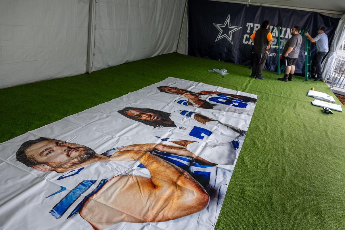 Cowboys contractors hang banners to get ready for fans at the team's training camp.