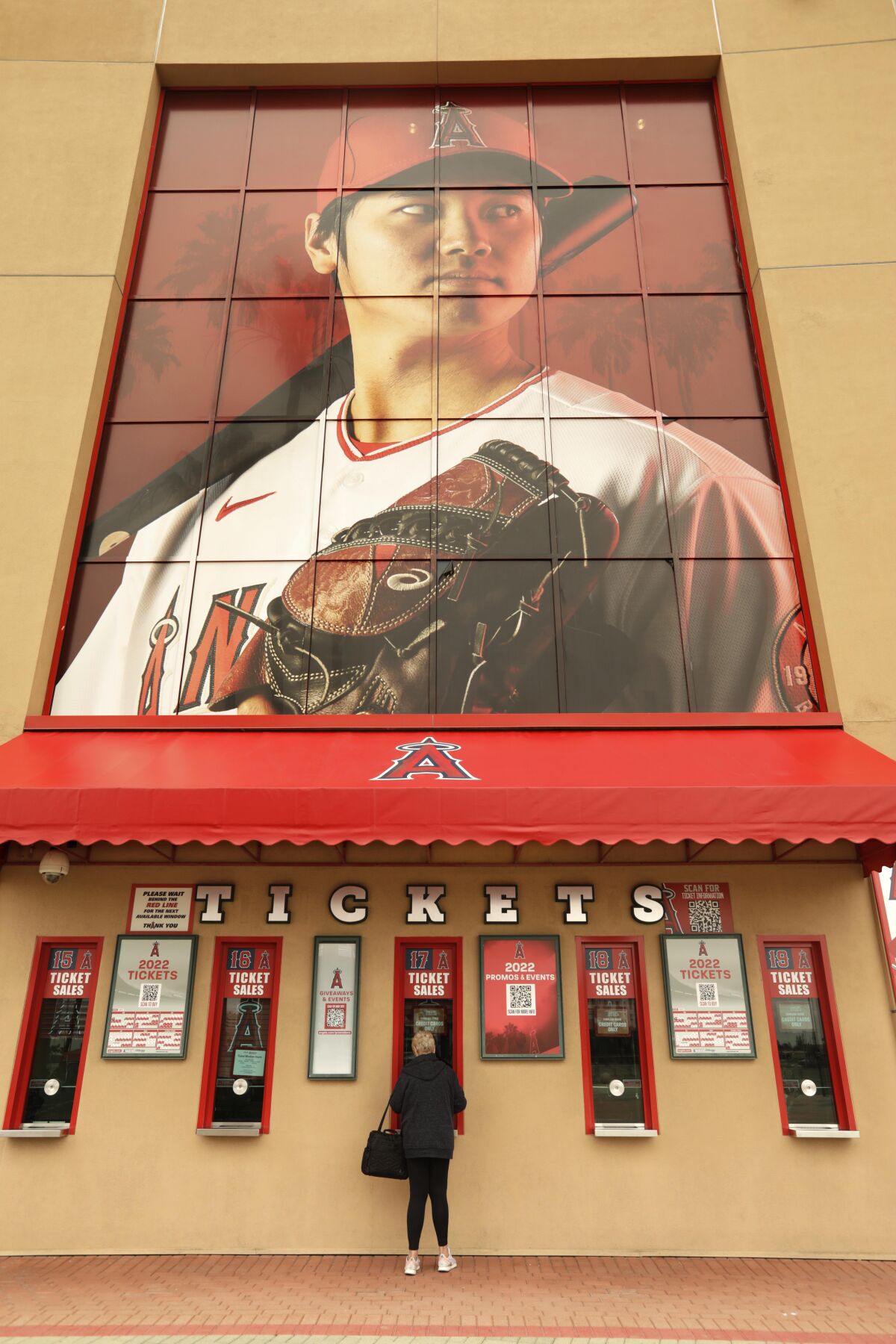 A fan buys tickets underneath a photo of Angels pictcher Shohei Ohtani at the main entrance to Angel Stadium