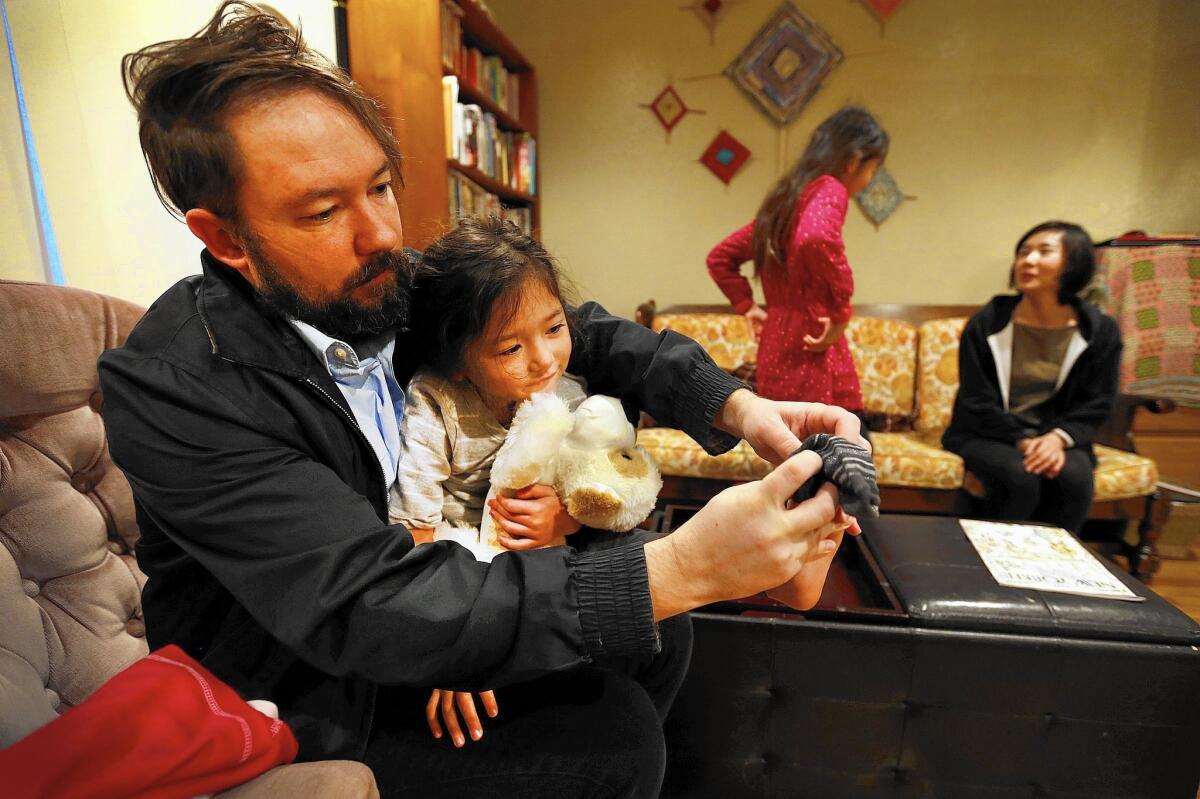 Nate Heneghan, helping his 4-year-old daughter Ada with her socks, is one of about 430 non-tenure-track faculty members at USC awaiting results of a vote on whether to be represented by SEIU Local 721.