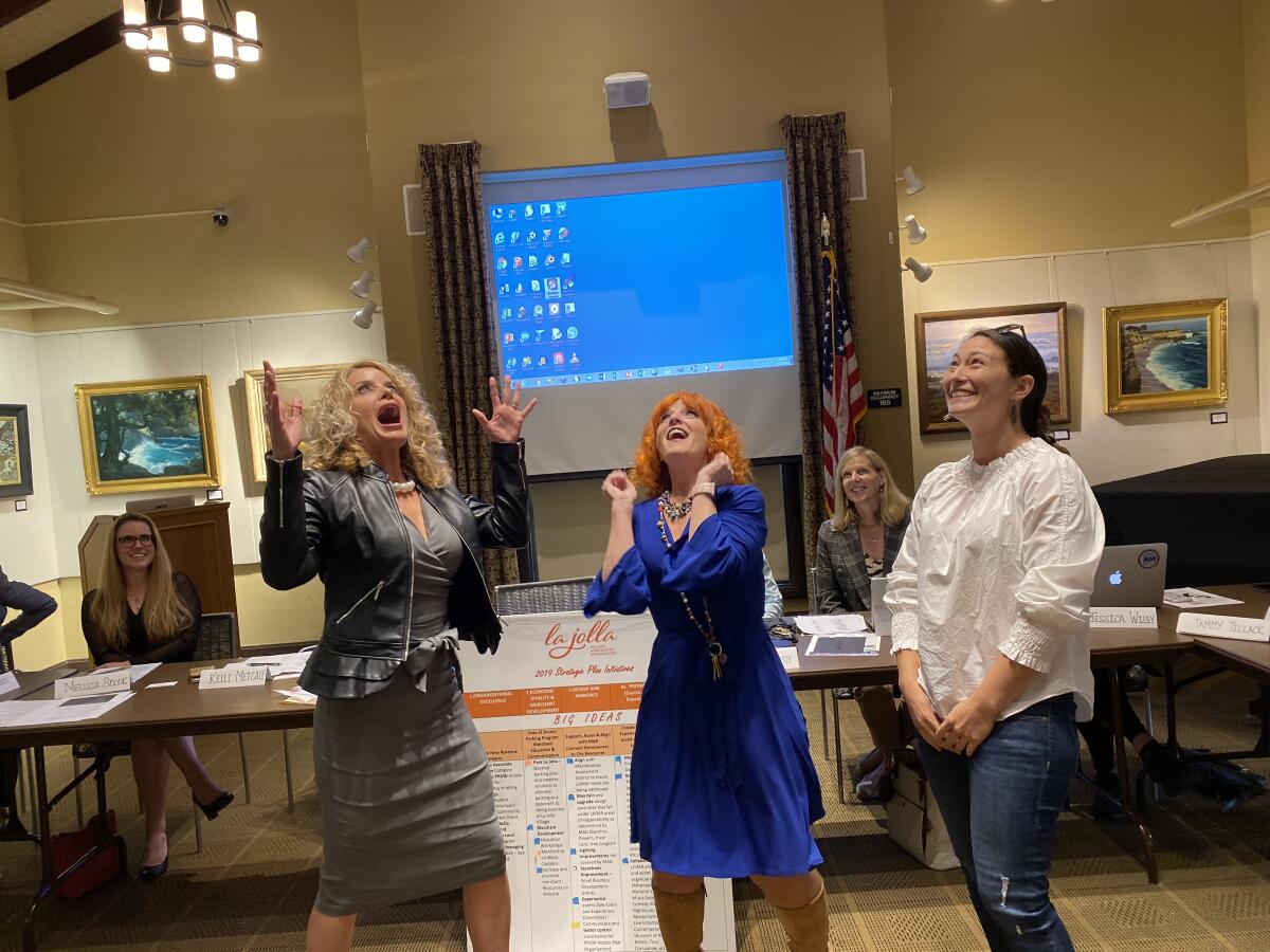 A coin tossed by La Jolla Village Merchants Association executive director Jodi Rudick, center, breaks the tie vote to determine the organization’s next treasurer between Kelli Metcalf and Lauren Johnston at the Nov. 13 meeting in the La Jolla Library.