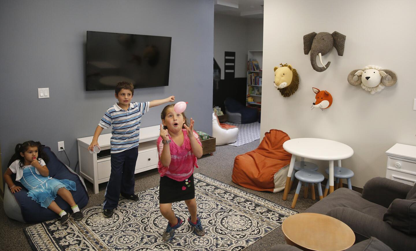 David Tsaturyan, 8, center, plays with his twin sister Diana Tsaturyan, 8, right, and sister Emily Tsaturyan, 4, left, in the living room of the new San Fernando Valley Rescue Mission decorated by interior designer Emily Henderson.
