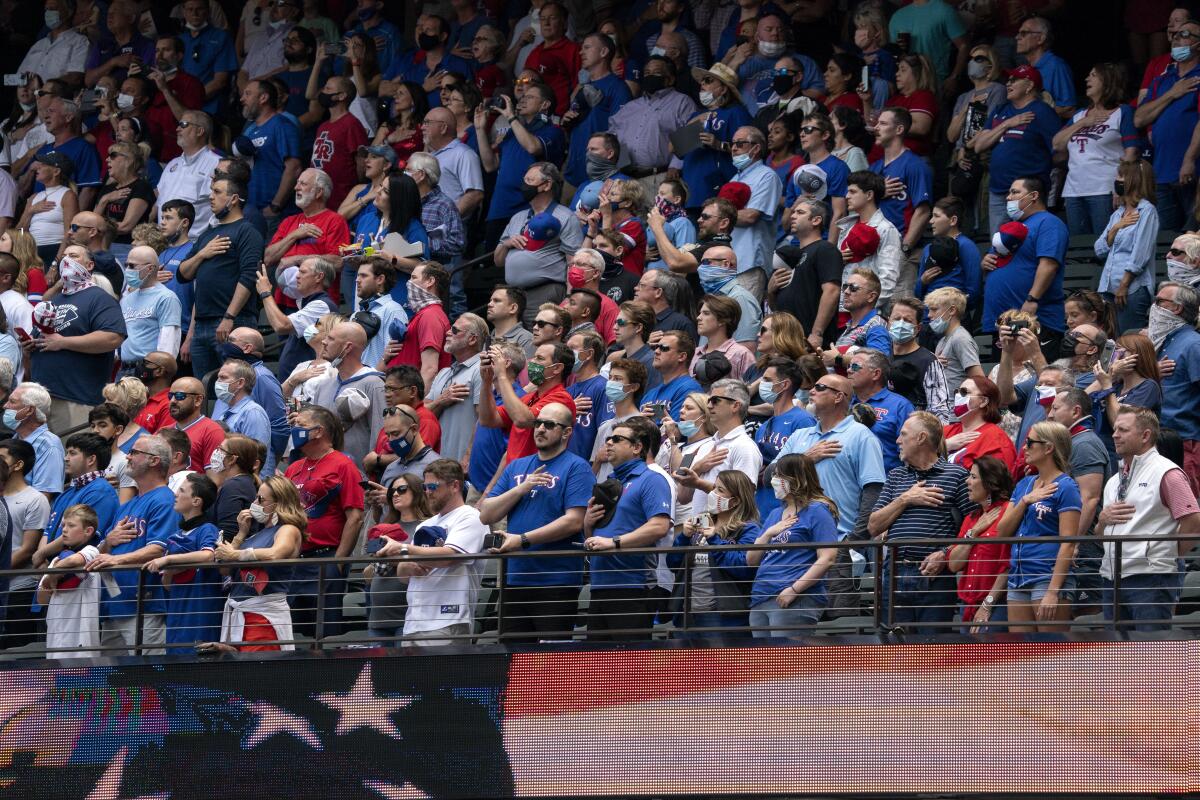 Aficionados de pie para el himno nacional antes del partido entre los Rangers de Texas y los Azulejos 