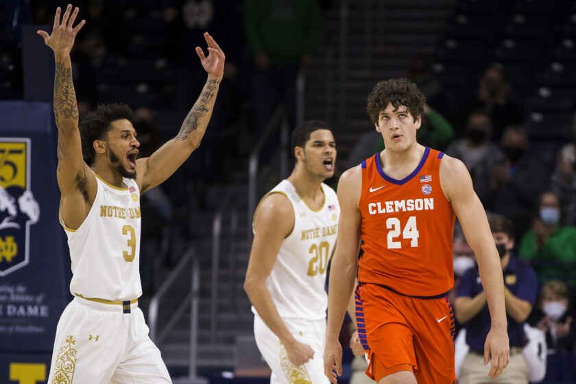 Clemson's PJ Hall (24) walks to his team's bench during a timeout as Notre Dame's Prentiss Hubb (3) and Paul Atkinson Jr. (20) celebrate an early lead during the first half of an NCAA college basketball game Wednesday, Jan. 12, 2022, in South Bend, Ind. (AP Photo/Robert Franklin)