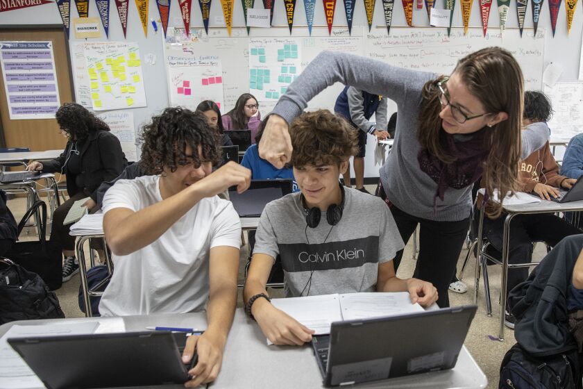 VAN NUYS, CA-NOVEMBER 17, 2022: William Lopez Rodas, left, sitting next to classmate Daniel Safa, both 10th graders at Birmingham High School in Van Nuys, receives a congratulatory fist bump from his teacher, Lindsay Humphrey, for referring to his notes during a computer science class offered by Stanford University. Birmingham High School and other L.A. schools are partnering with the National Education Equity Lab to offer Ivy League courses to underserved high school students. (Mel Melcon / Los Angeles Times)