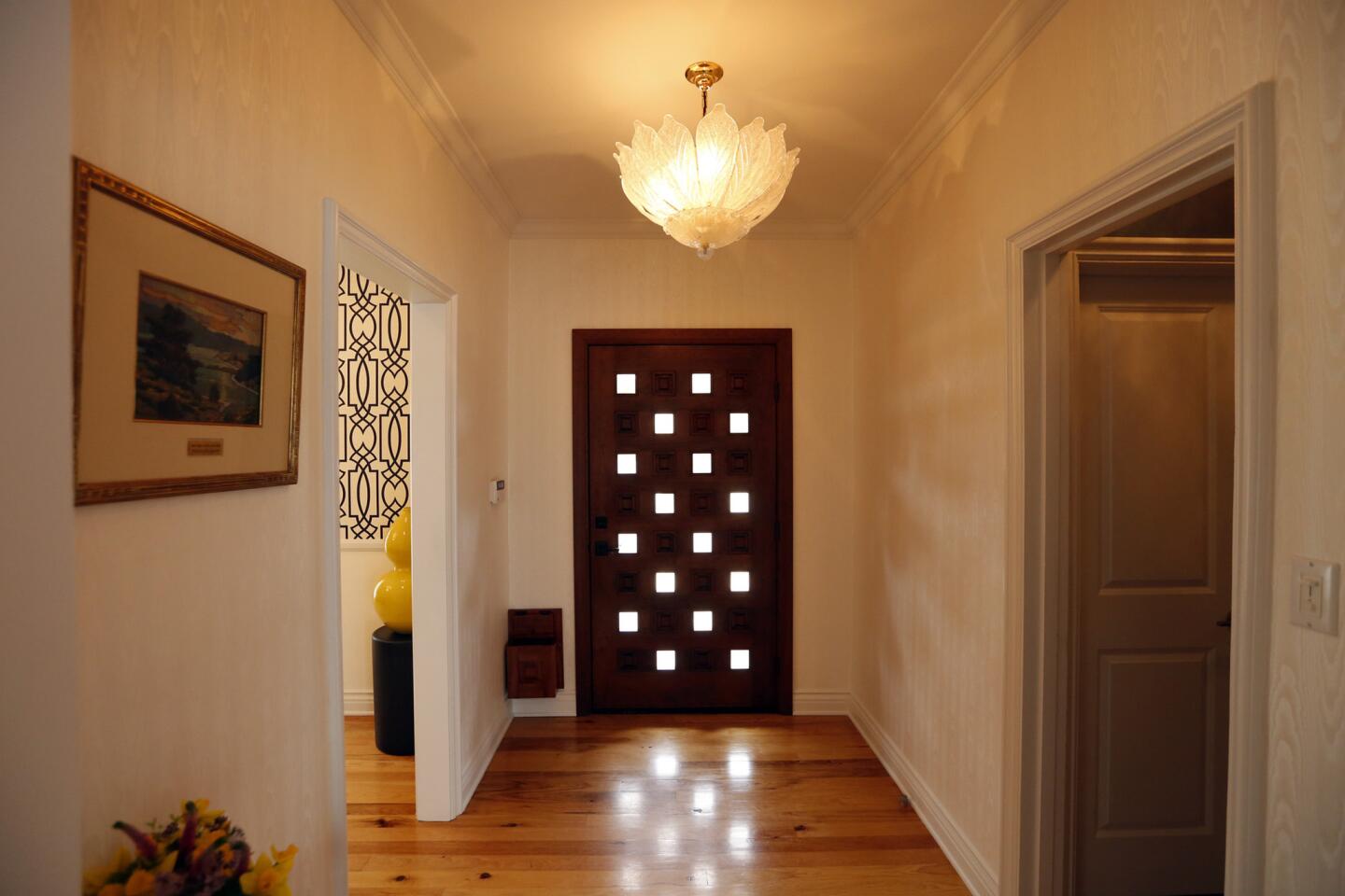 The entryway includes another Murano glass lighting fixture as well as a wood door with glass placed