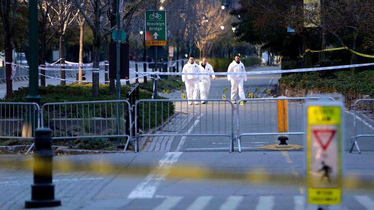 Emergency officials walk near evidence markers at the scene where a motorist drove onto a bike path in Lower Manhattan earlier this week, killing eight..