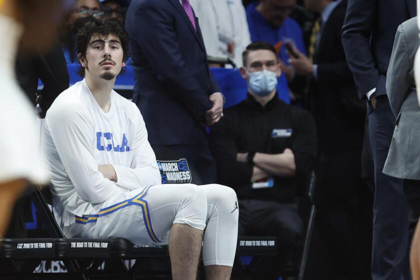 UCLA's Jaime Jaquez Jr. sits on the bench with ice on his ankle after leaving the court with an injury March 19, 2022.