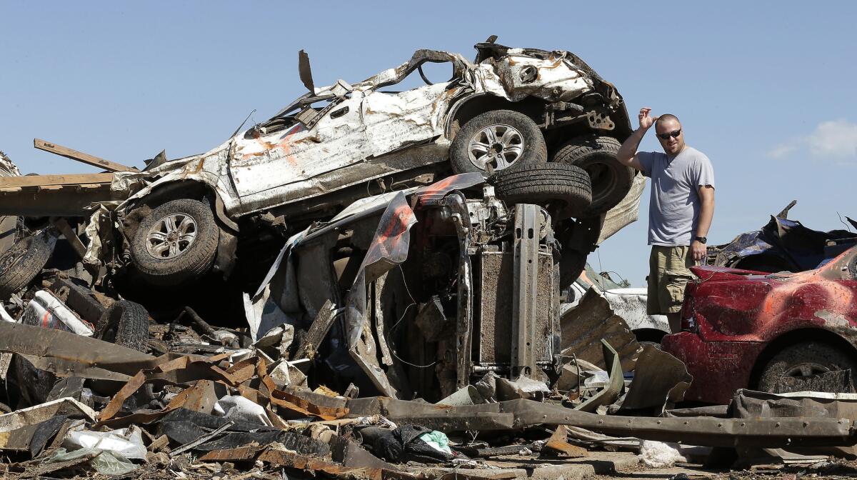 Eric Lowery looks at tornado-ravaged vehicles while retrieving items from his mother's car at a destroyed strip mall. Cleanup continues two days after a huge tornado roared through the Oklahoma City suburb of Moore.