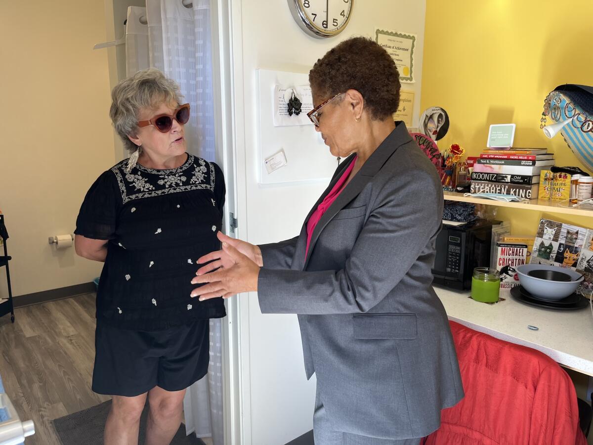 Two people stand and talk in a kitchen.