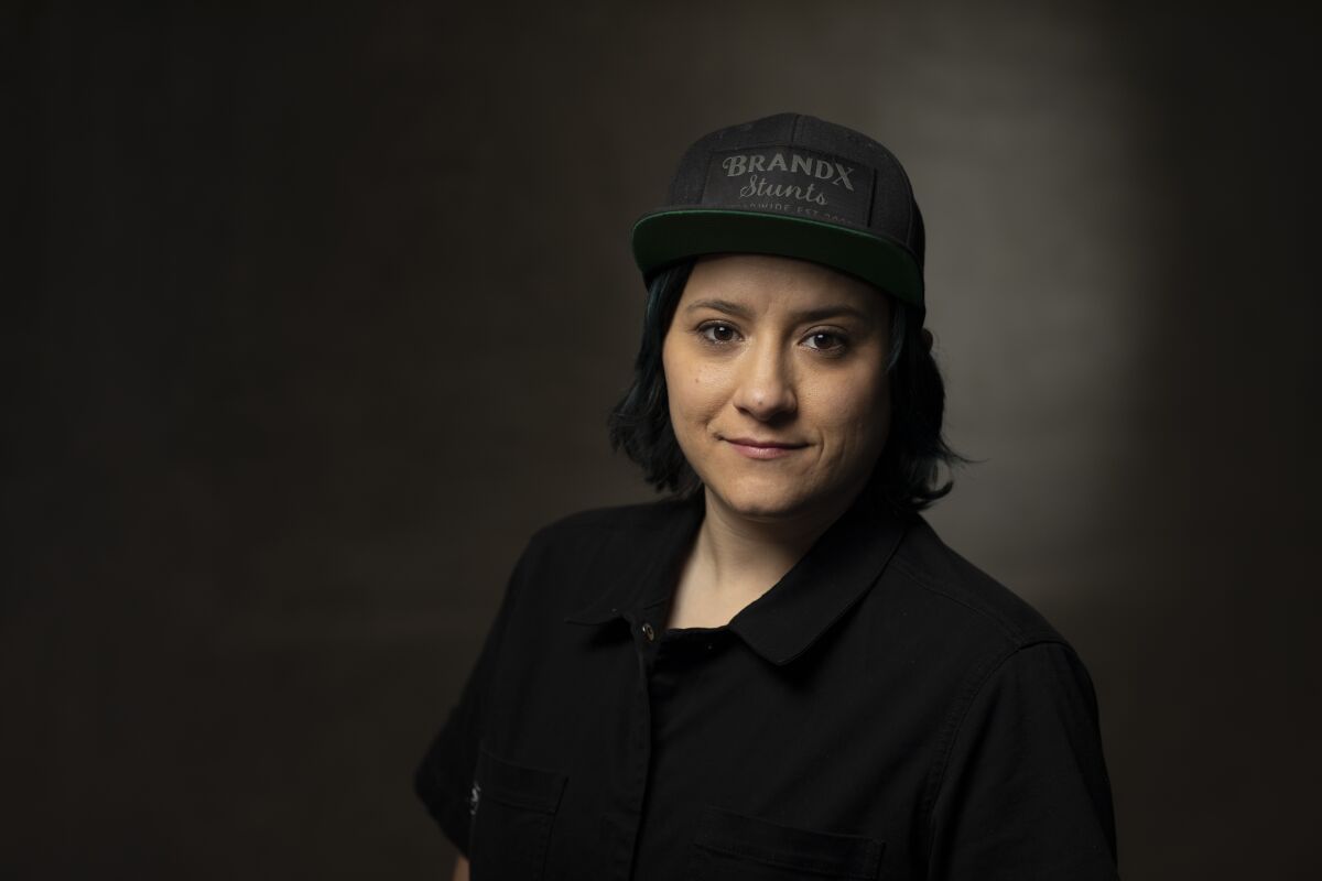 A woman dressed in black and wearing a black baseball cap
