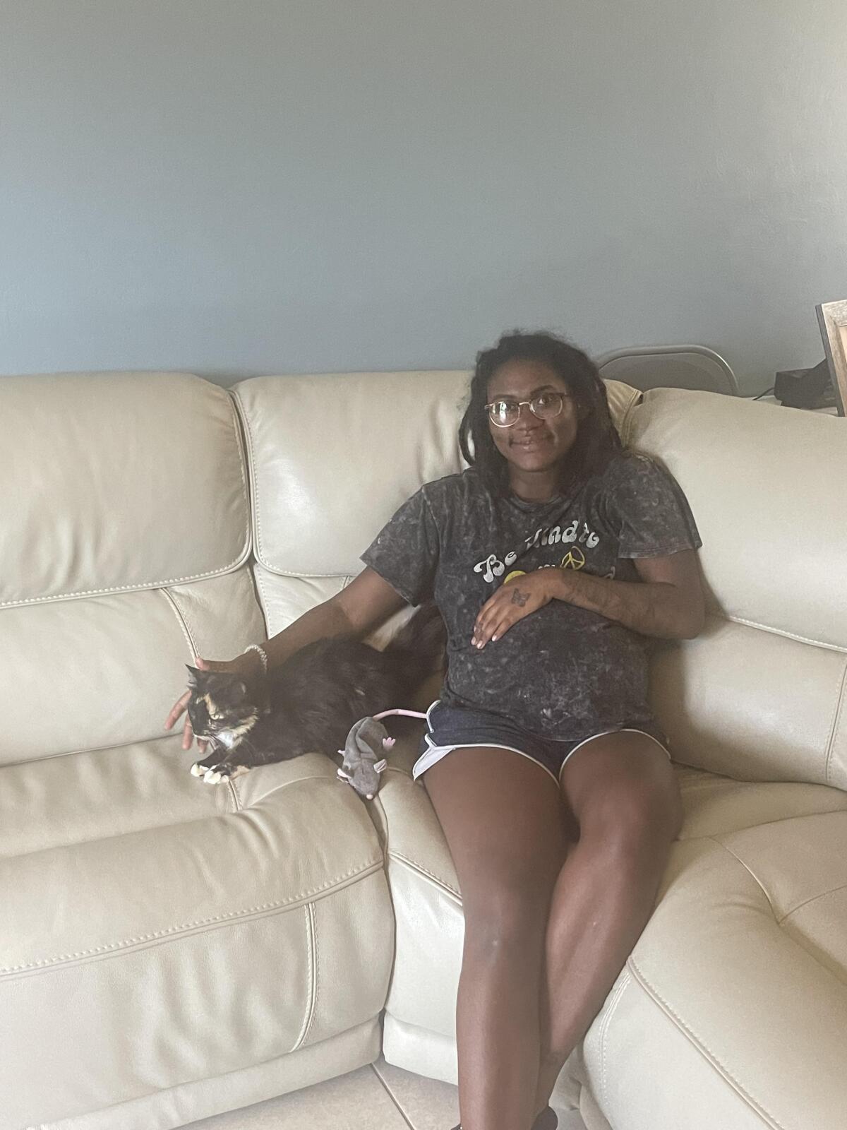 Alonna Meletiche sits on the couch with the family cat Baby, who had been missing for 10 months.