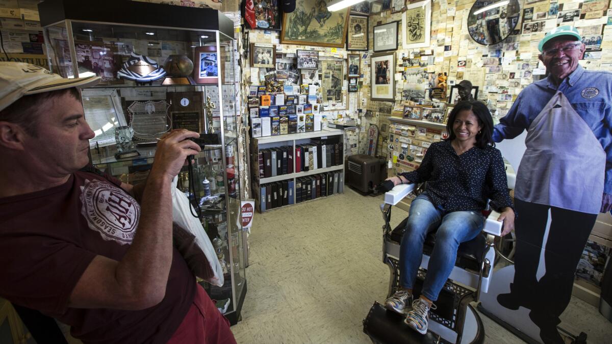 Visitors pose for photos with a cardboard likeness of Angel Delgadillo in his barber shop in Seligman, Arizona. (Brian van der Brug / Los Angeles Times)