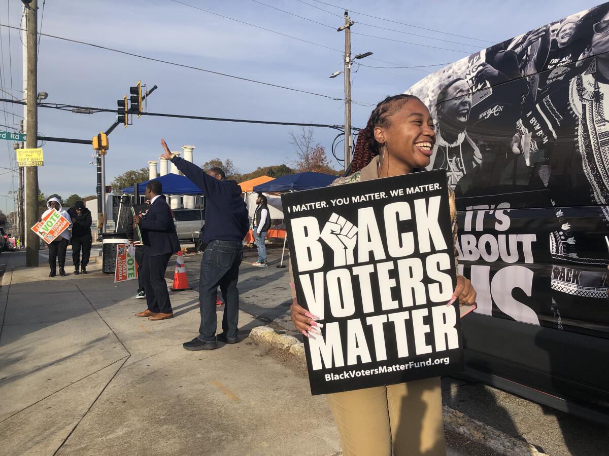 A woman holds up a sign reading, "Black Voters Matter" 