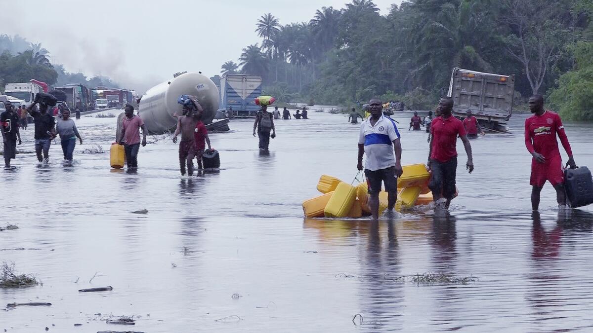 ARCHIVO - Numerosas personas se desplazan por caminos inundados tras intensas lluvias en Bayelsa, Nigeria,