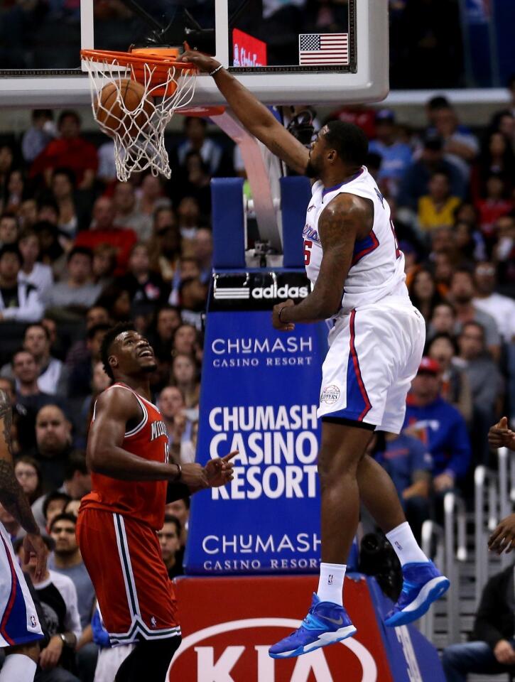 Clippers center DeAndre Jordan, right, dunks over Milwaukee Bucks forward Jeff Adrien during the first half of Monday's game at Staples Center.