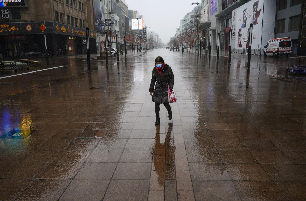 In February, a woman walks through a nearly-empty shopping area in Beijing.