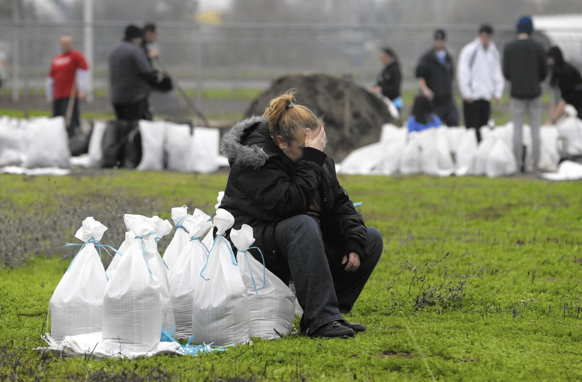 Kathryn Olson rests on a sandbag before carrying it to her vehicle to be used at her home in the Sacramento suburb of North Highlands.