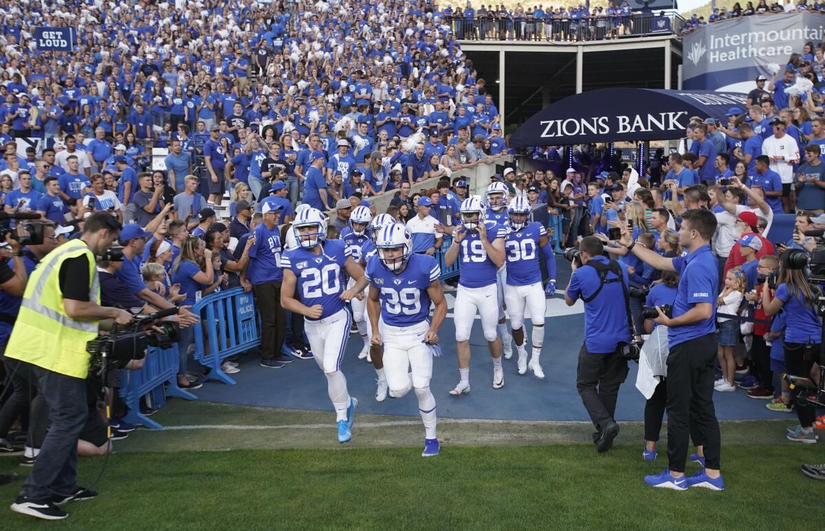 FILE - BYU football players enter the field to warm up for an NCAA college football game against Utah in Provo, Utah, in this Thursday, Aug. 29, 2019, file photo. A deal BYU has made available to its football players could test how much allowing athletes to be compensated by outside companies for name, image and likeness can be used as a competitive advantage. On Thursday, Aug. 12, 2021, BYU announced Built Brands —- a Utah-based company that makes protein-heavy snacks —- will give the opportunity for all 123 members of its football team to be paid to promote its products. (AP Photo/George Frey, File)