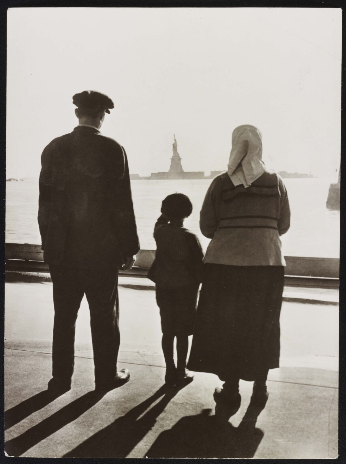 A photo shows an immigrant family looking at Statue of Liberty from Ellis Island.