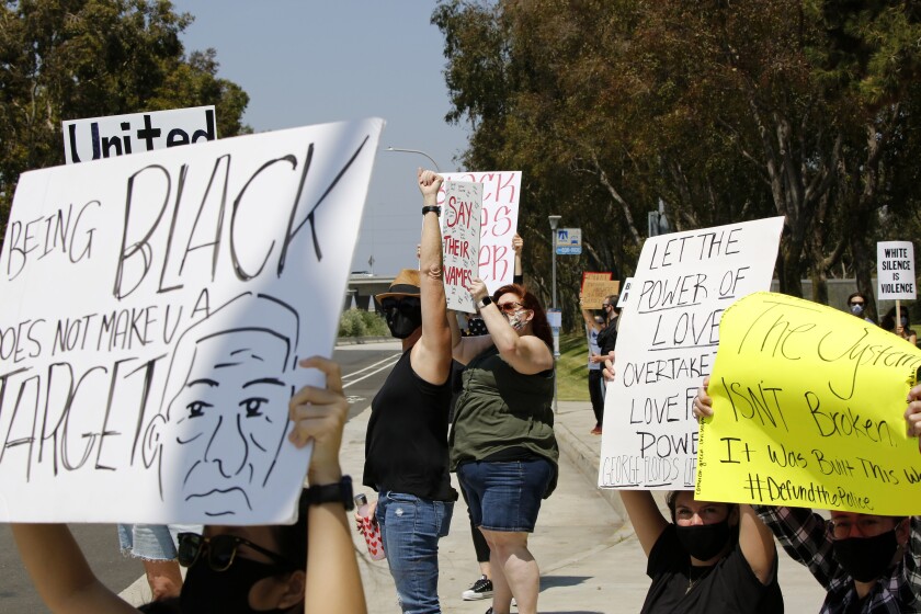 Protesters hold signs during a Black Lives Matter rally at Bonita Creek Park in Newport Beach on Saturday. 