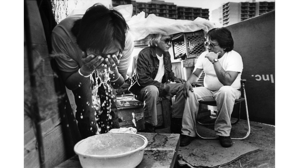 Feb. 5, 1984: Wilma Aros washes up as Jack Yazzie, center, and Franklin Whiterock chat. Water comes from plastic jugs. Whiterock, 29, spent six years in the U.S. Marines, including two in Vietnam.