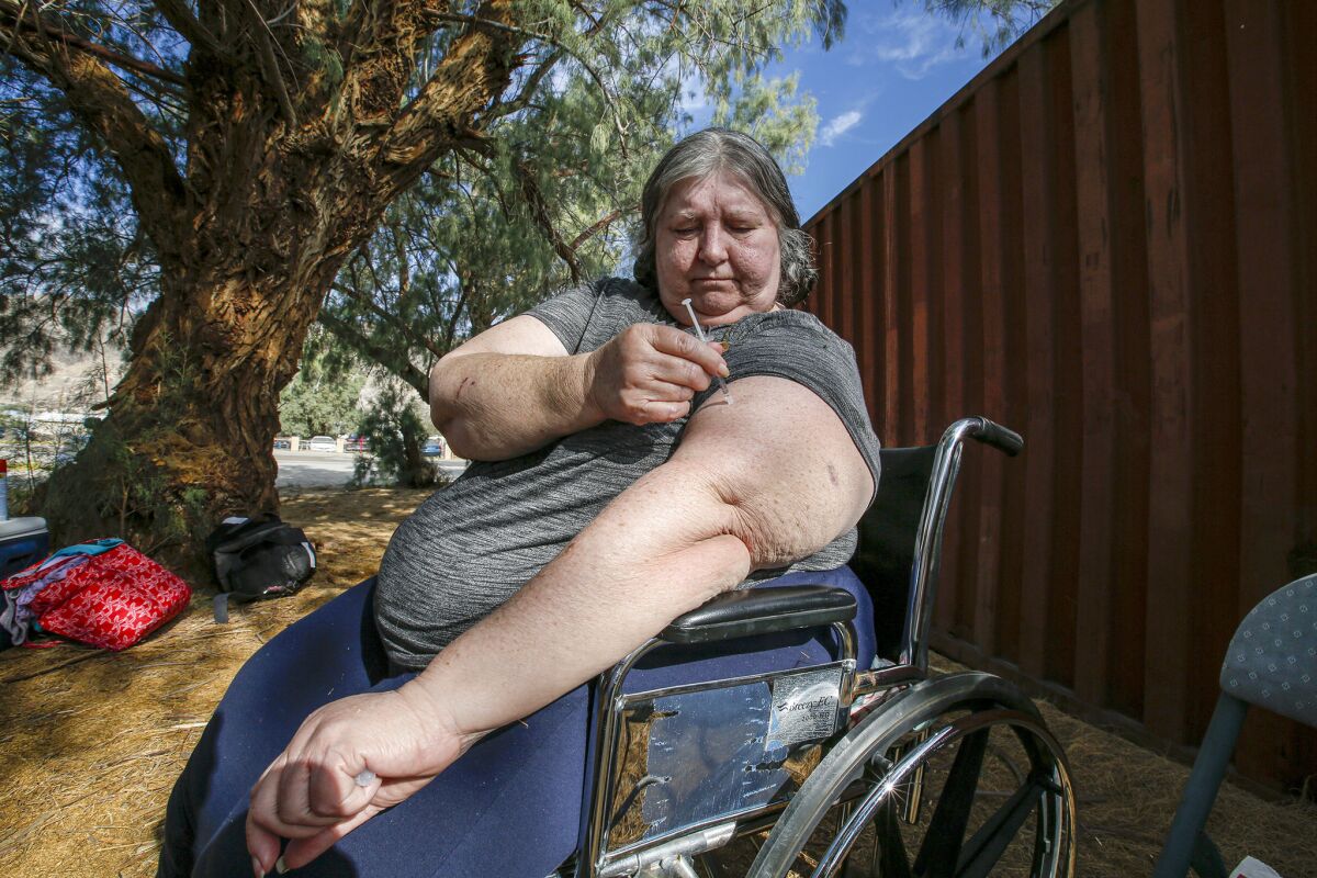 Kay Byrd, 64, gives herself an insulin shot. Byrd and her family are camping outside in Trona, Calif., wary of returning home after major earthquakes. (Irfan Khan / Los Angeles Times)