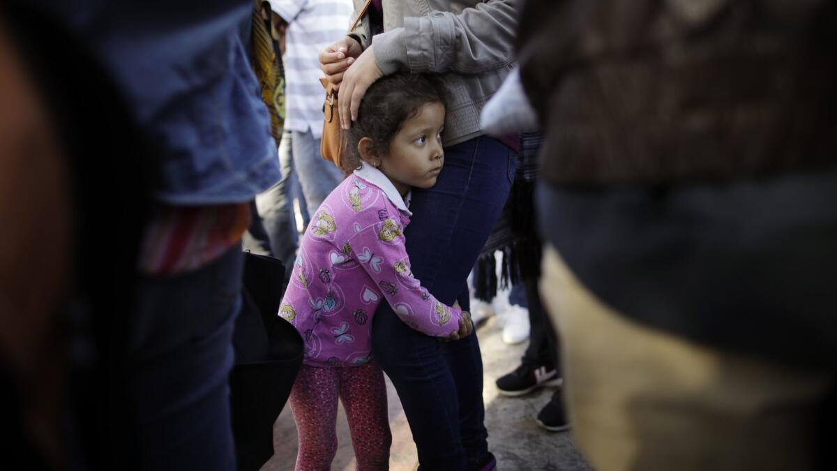 Nicole Hernandez holds on to her mother on June 13 as they wait with other families to request political asylum in the United States, across the border in Tijuana, Mexico.