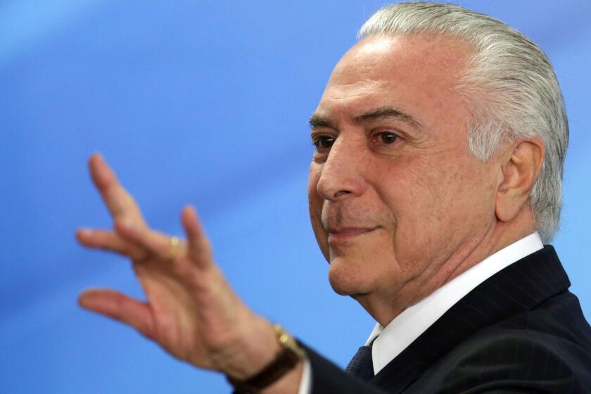 Brazil's President Michel Temer waves as he exits after attending a ceremony at the Planalto Presidential Palace, in Brasilia, Monday, June 26, 2017. Temer is expressing defiance in the face of possible corruption charges, the lowest approval rating for a Brazilian leader in a generation and calls for his resignation. He says nothing will "destroy" his government. (AP Photo/Eraldo Peres)