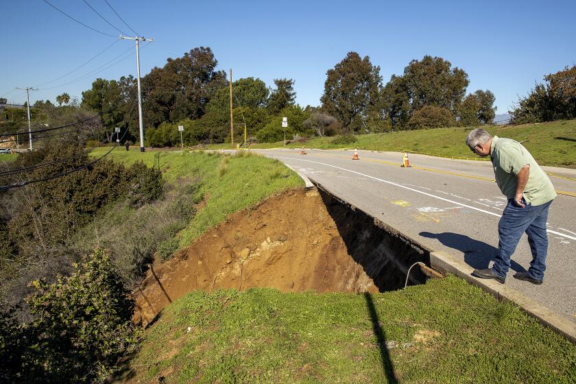 BEVERLY HILLS, CA-JANUARY 6, 2023:Jason Darby, a supervisor with the Los Angeles Dept. of Water and Power, gets a closer look at a landslide on Mullholland Dr. near Summit Circle in Beverly Hills, caused by the recent rains. (Mel Melcon / Los Angeles Times)