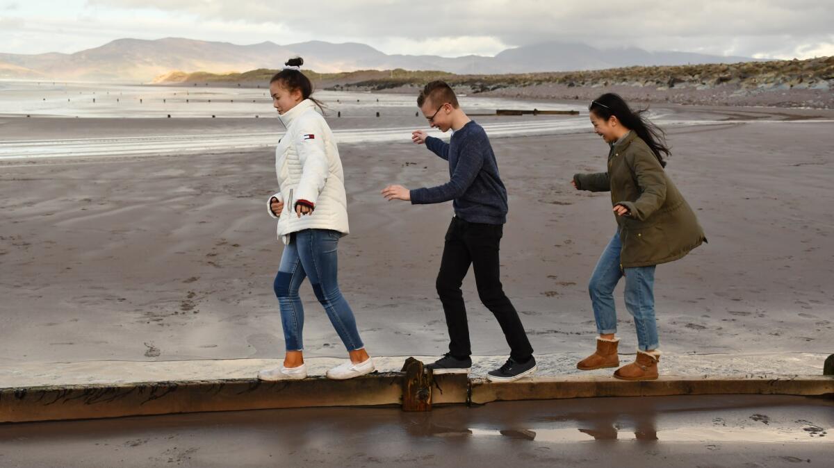 Three teens test their balance at Rossbeigh Beach, County Kerry.