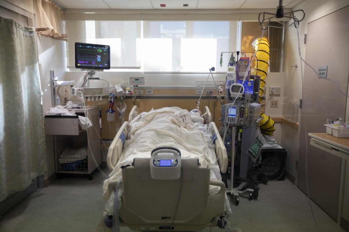 A patient with COVID-19 lays inside a negative pressure room inside a hospital's ICU.