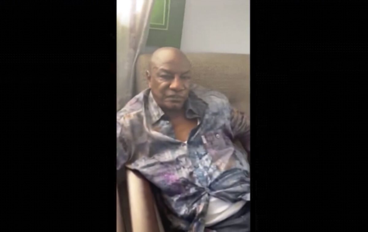 In this image made from video on Sunday, Sept. 5, 2021, Guinean President Alpha Conde sits on a sofa in an unknown location. Footage posted on social media showed Guinea's president Alpha Conde in a room and sat next to a soldier on Sunday, as a Guinean army colonel seized control of state television and declared that Conde's government had been dissolved. It was not immediately clear at what stage the video was taken. (UGC via AP)