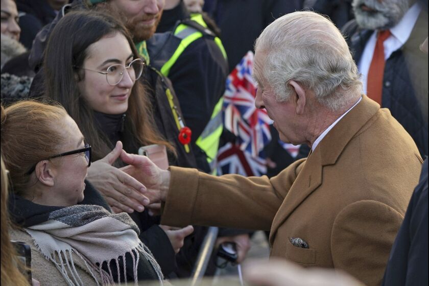 Britain's King Charles III, right, greets members of the public as he arrives for a visit to Luton Town Hall, where he is meeting community leaders and voluntary organisations, in Luton, England, Tuesday, Dec. 6, 2022. (Yui Mok/PA via AP)