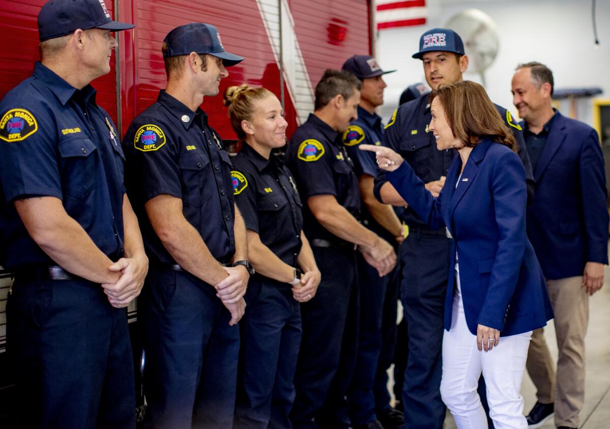 Firefighters stand next to a fire truck in a receiving line for Vice President Kamala Harris