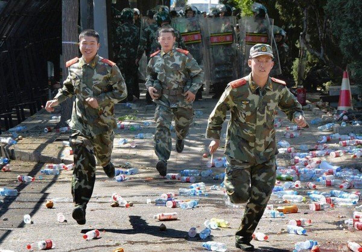 Paramilitary police run past bottles thrown by demonstrators outside the Japanese Embassy in Beijing this week.