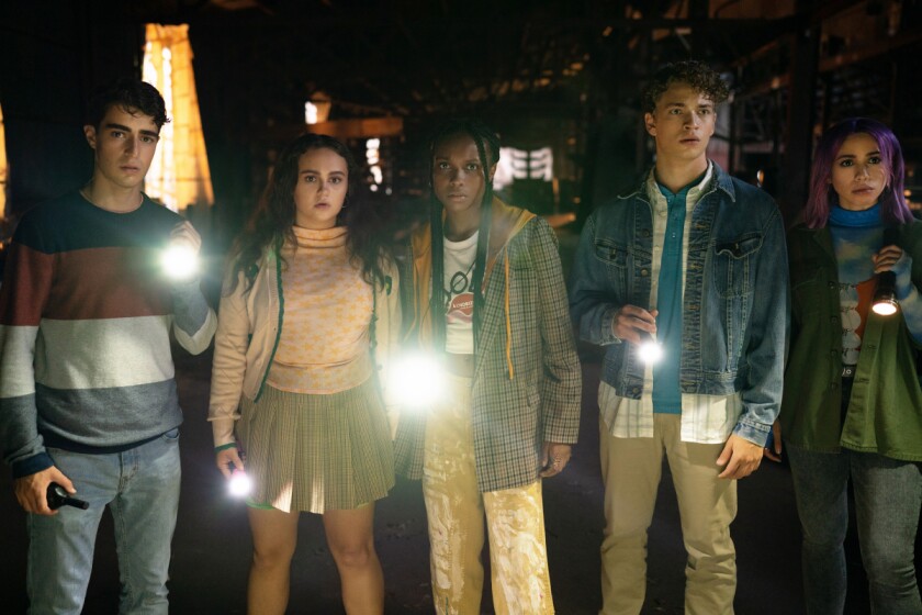 Five people holding shining flashlights stand side by side.