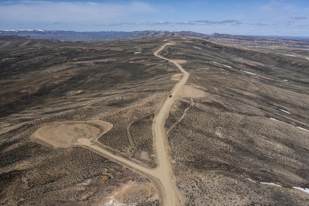 An aerial view of flat landscape stretching into the distance with a dirt road snaking through.
