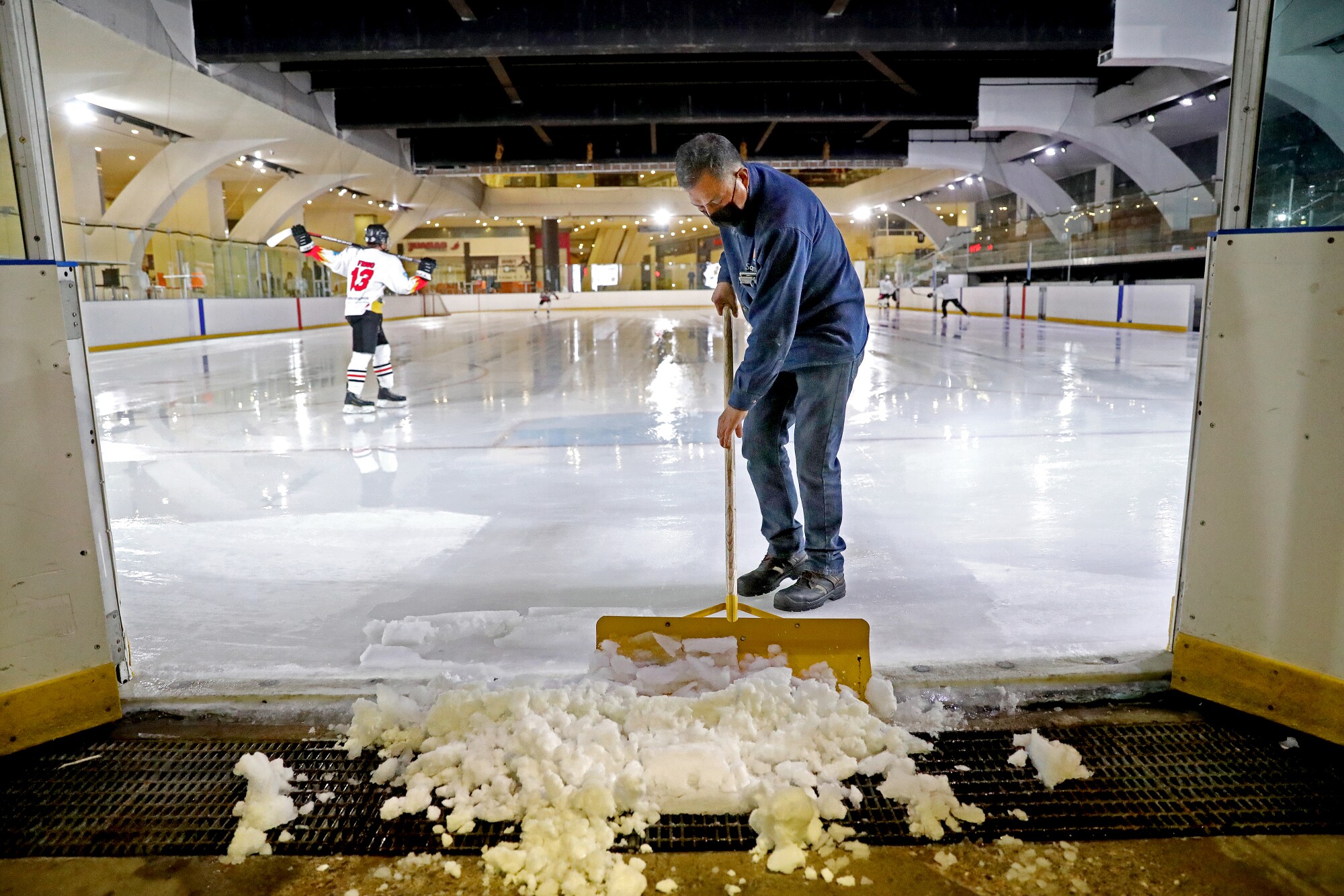 Apolinar Lopez clears off the extra ice after driving the Zamboni in preparation for a scrimmage.