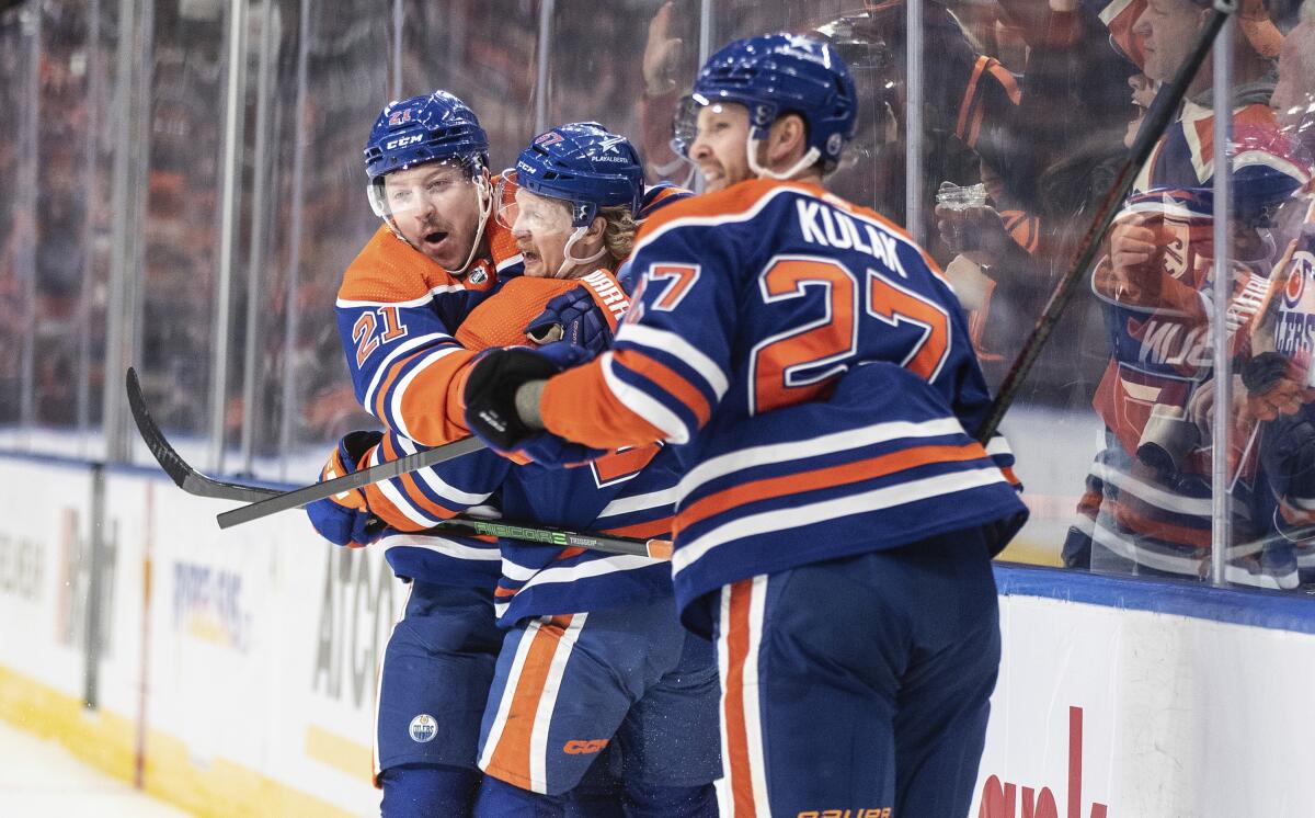 Edmonton Oilers' Adam Erne (21), James Hamblin (57) and Brett Kulak (27) celebrate a goal against the Anaheim Ducks Sunday.