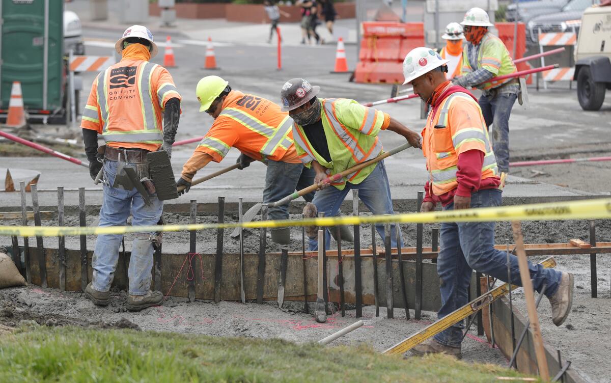 Workers pour and fill new cement, making a sidewalk as Caltrans finishes a project in Laguna Beach in May. 
