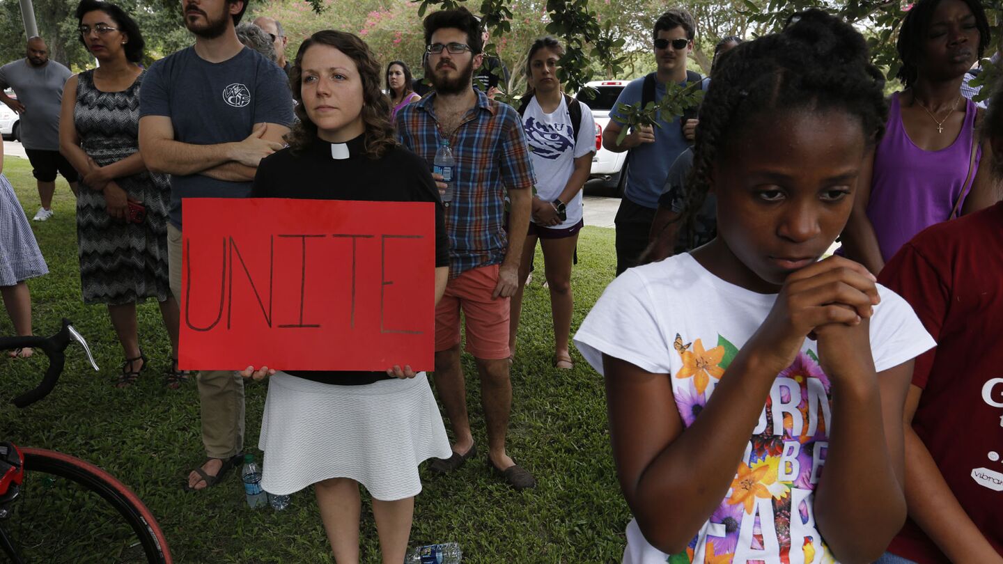 Surrounded by members of the Baton Rouge community, Methodist pastor Colleen Bookter holds a sign that says UNITE during a vigil on the LSU campus Wednesday.