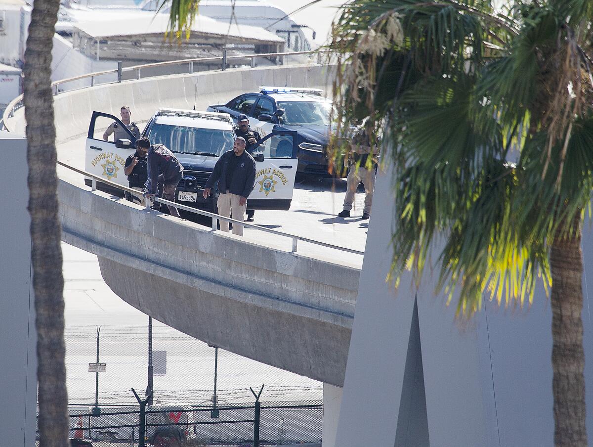 A man standing on the railing of a freeway ramp as officers approach