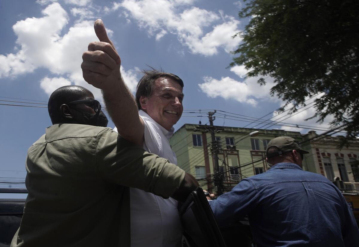 Brazilian President Jair Bolsonaro greets supporters after voting during municipal runoff elections in Rio de Janeiro.