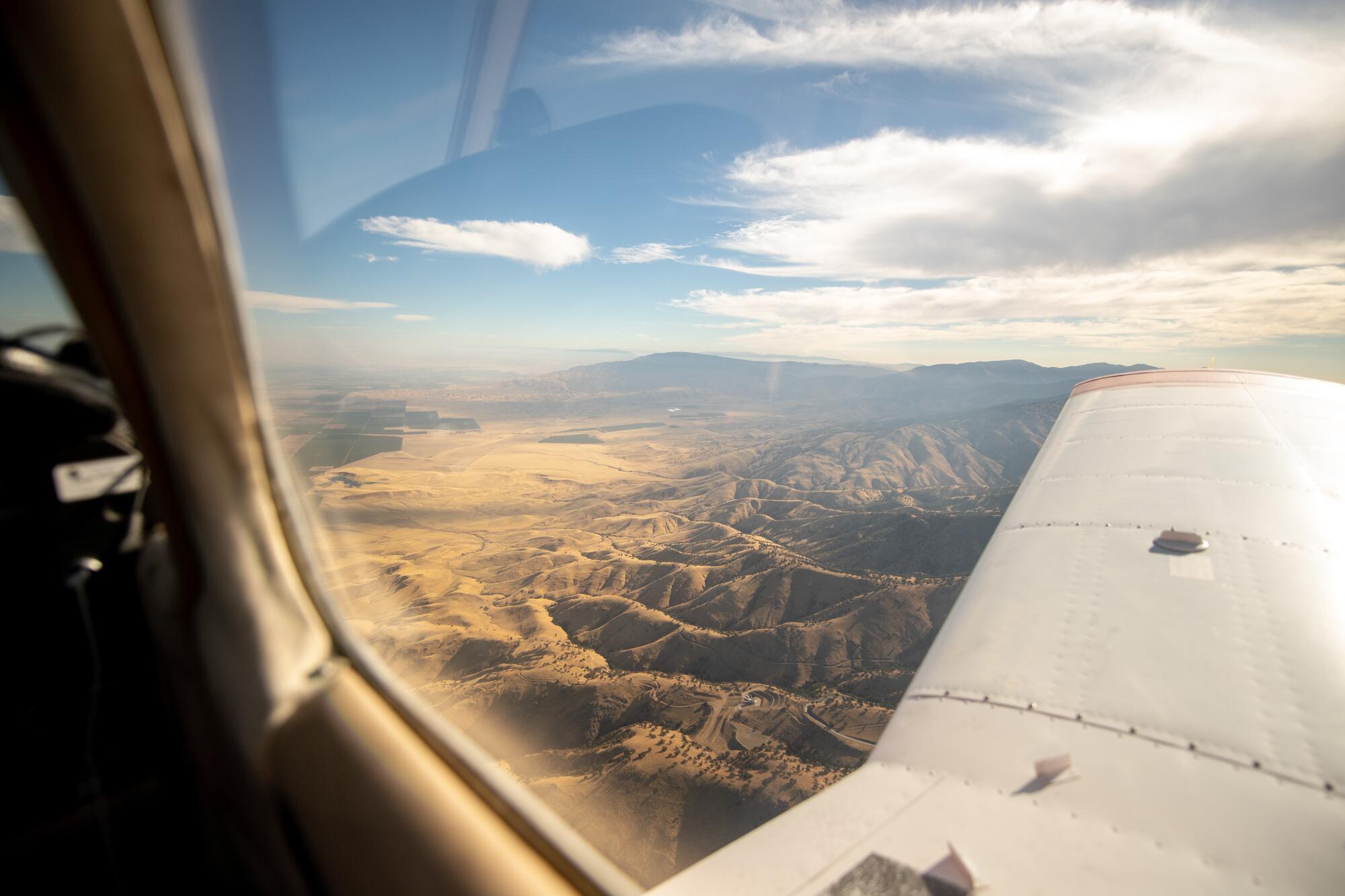 The California landscape, illuminated by the morning light, seen from the window of an airplane.