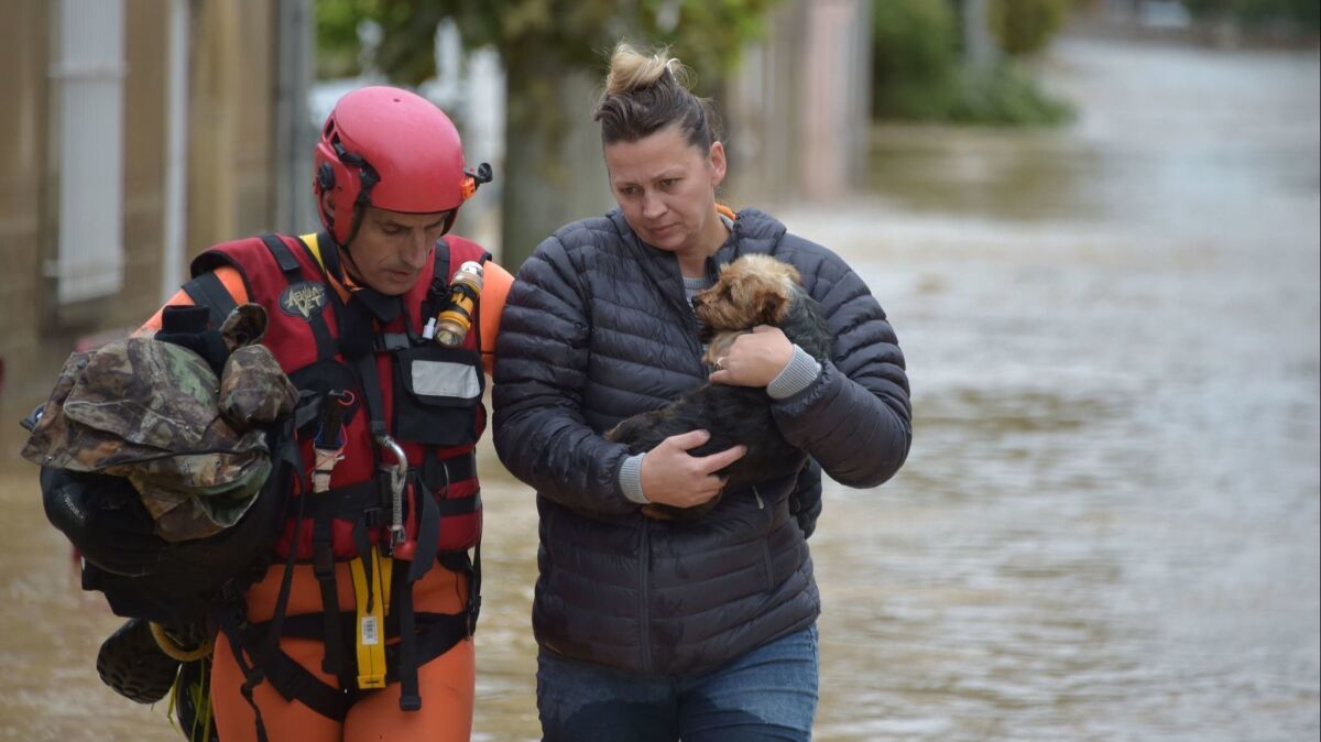 A rescuer helps a resident holding a dog following heavy rains that saw rivers bursting banks on Oct. 15 in Trebes, France.