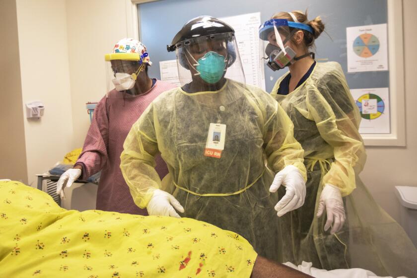 LOS ANGELES, CA - May 7: Radily Quinnece Washington, 31, Covid19 Unit RN, left, Naomi Okonofua, 24, ICU RN, middle, and Amanda Hamilton, 29, ICU RN working together in the ICU at Martin Luther King, Jr., Community Hospital on Thursday, May 7, 2020 in the Willowbrook neighborhood located in South Los Angeles, CA. A patient was brought from the covid19 unit into the ICU. The medical workers are helping one another as they work as a team during the global coronavirus pandemic. (Francine Orr / Los Angeles Times)