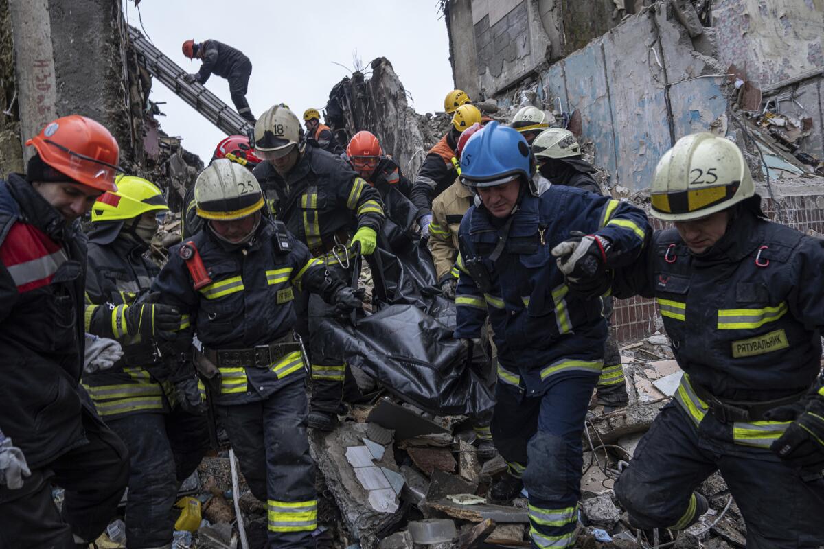 Workers carry a body from the rubble of an apartment building.