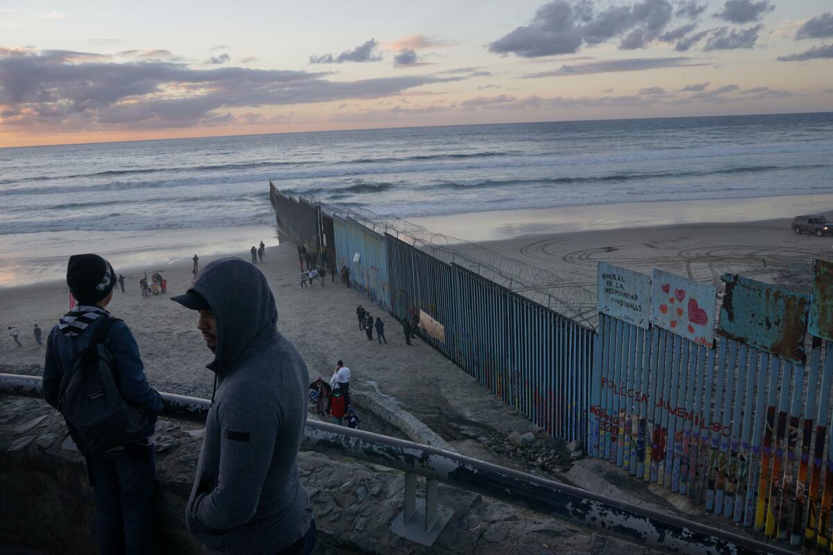 People gather near the U.S.-Mexico border fence in the Las Playas Area on Sunday in Tijuana.